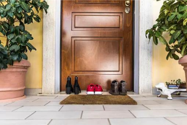 Shoes lined up in front of a closed front door